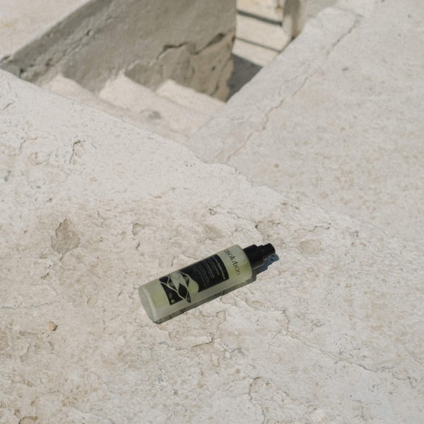 Absolution La Brume Systémique tonic spray liggend op een betonnen vloer voor een minimalistische, moderne uitstraling.