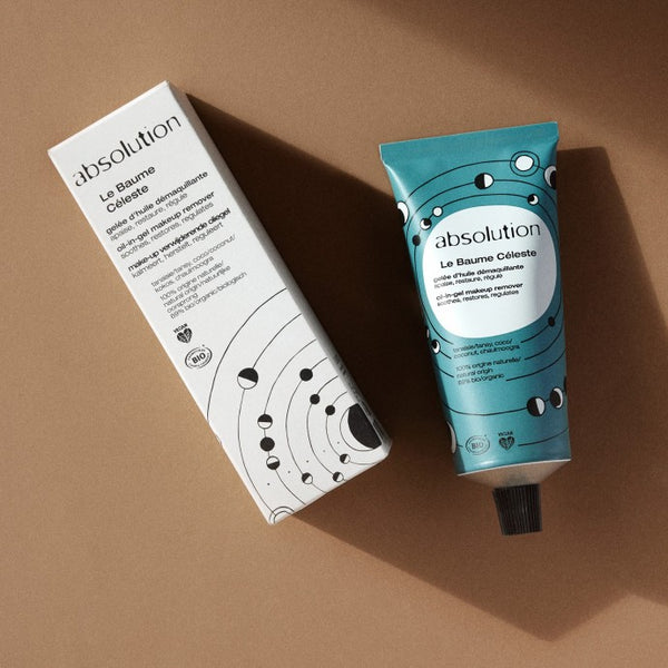 Sfeerbeeld van de tube en verpakking van Absolution Le Baume Céleste met beige achtergrond en schaduwen