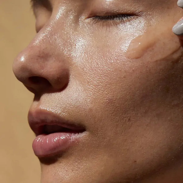 Model met een veeg Le Sérum Anti-Soif van Absolution Cosmetics op haar gezicht, om de lichte en hydraterende textuur te tonen