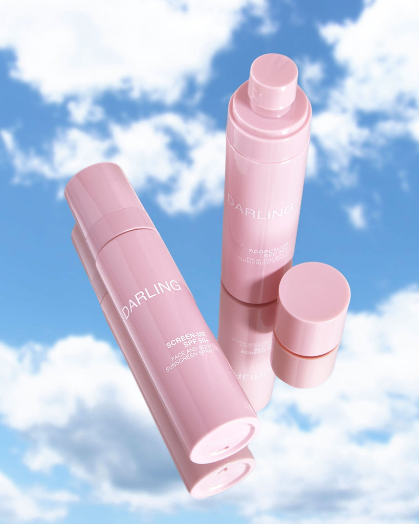 Twee Darling Screen-Me SPF 50 sprays op een spiegel, één liggend zonder dop