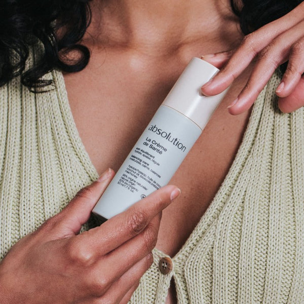 Vrouw houdt La Crème de Santé van Absolution Cosmetics vast, klaar voor gebruik