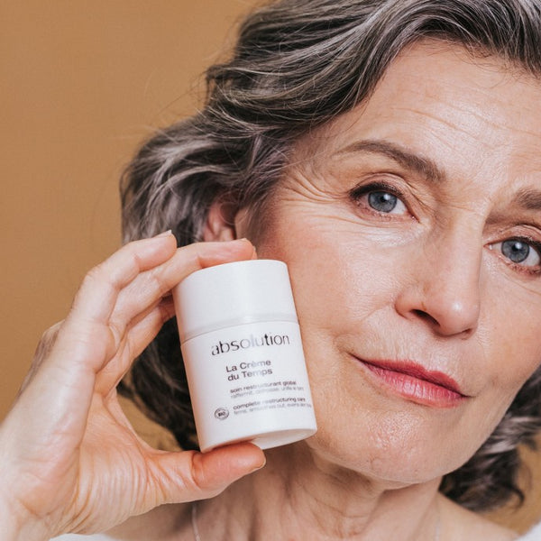 Vrouw houdt La Crème du Temps anti-aging crème van Absolution Cosmetics tegen haar gezicht voor een jeugdige uitstraling