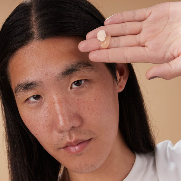 Model houdt La Crème Beau Jour en Le Masque Velours Repulpant van Absolution Cosmetics omhoog met zichtbare crème- en maskerteksturen