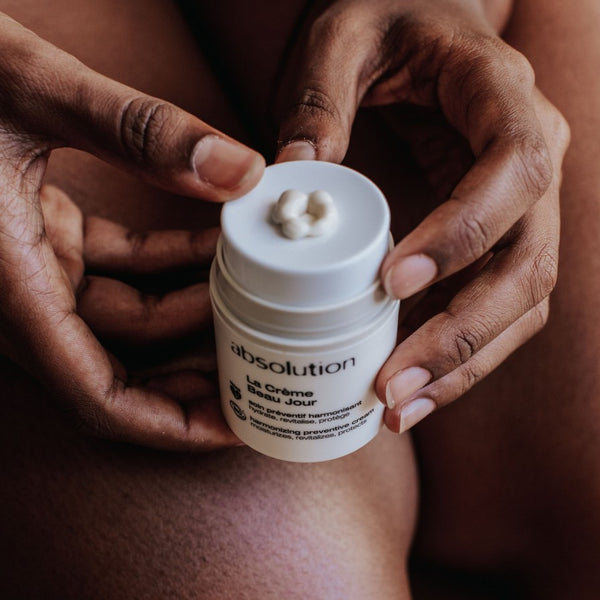 Hand die op het pompje van La Crème Beau Jour van Absolution Cosmetics drukt, voor gecontroleerde dosering van de hydraterende crème