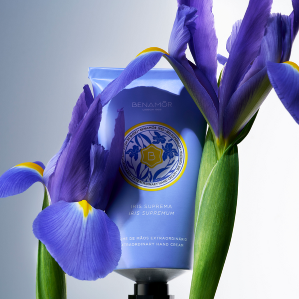 Close-up van een bloem met de Benamôr Iris Suprema handcrème op de achtergrond.