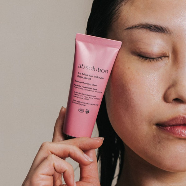 Na-foto van het model met een stralende, gehydrateerde huid, houdt de Le Masque Velours Repulpant tube tegen haar gezicht