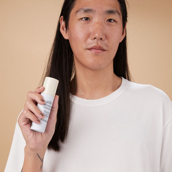 Man houdt Le Sérum Anti-Soif vast, klaar voor gebruik in zijn dagelijkse huidverzorging