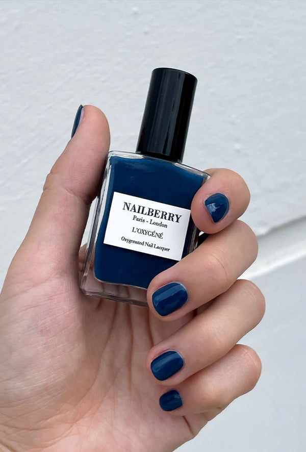 Model met Orage nagels, houdt een flesje Nailberry vast