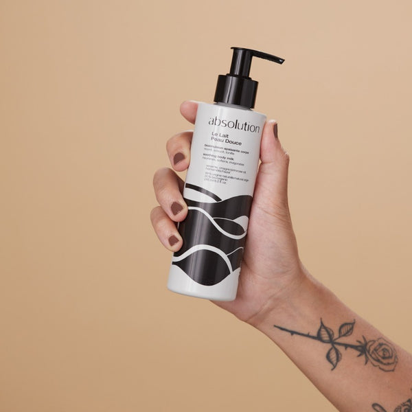 Hand die Absolution Le Lait Peau Douce bodymilk vasthoudt