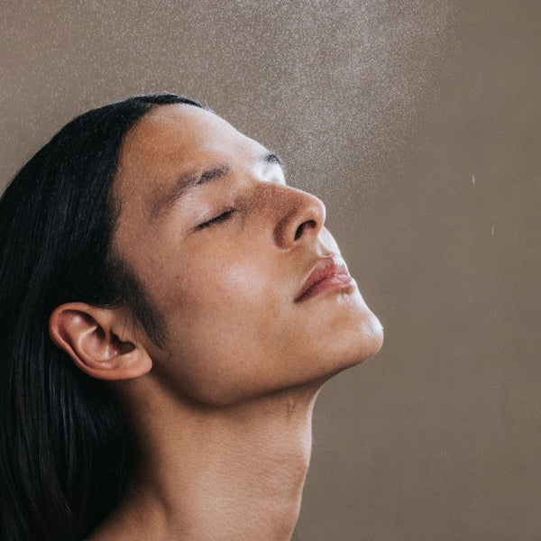 Vrouw sprayt La Brume Systémique zacht op haar gezicht voor een hydraterende nevel