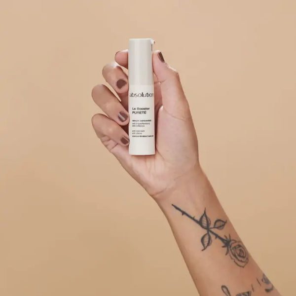 Iemand die Le Booster Pureté in de hand houdt en het pompje indrukt voor gebruik