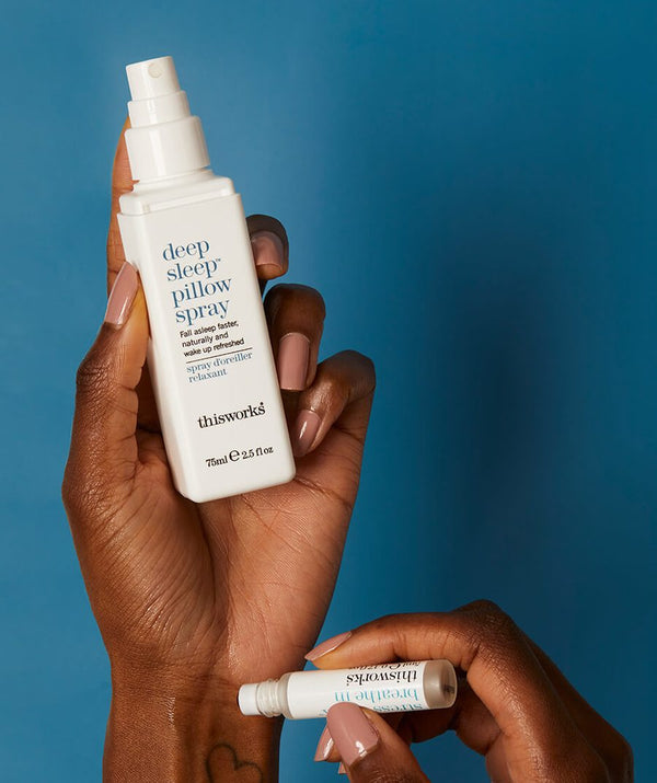 De twee producten van de This Works Deep Sleep Pillow Talk in de handen van een persoon.