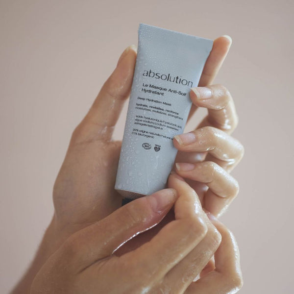 Iemand die de tube Le Masque Anti-Soif Hydratant tussen beide handen houdt