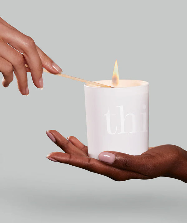 Hand houdt de Deep Sleep Heavenly Candle van This works vast terwijl een ander de kaars aansteekt met een lucifer
